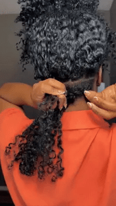 A Black women holding a section of curly crochet hair